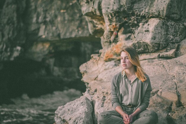 Фото Задумчивая женщина, отворачивающаяся от скалы.