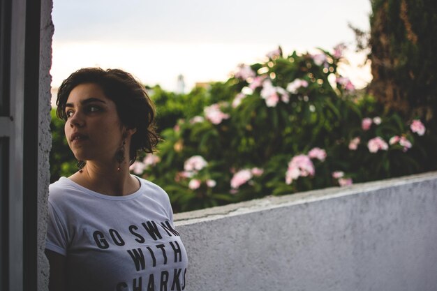 Thoughtful woman looking away while standing by retaining wall