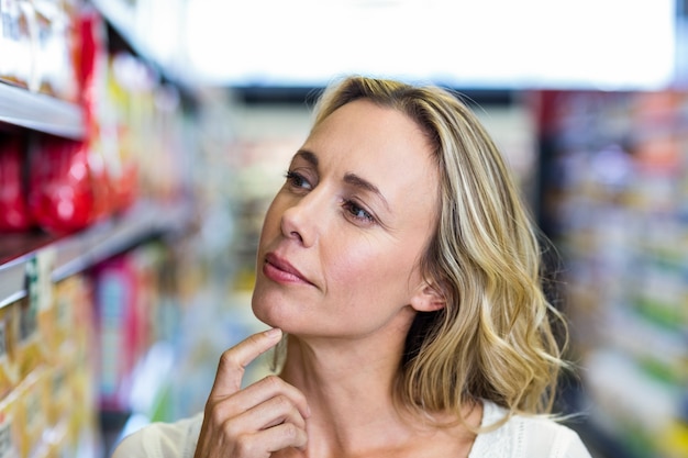 Thoughtful woman looking at shelves