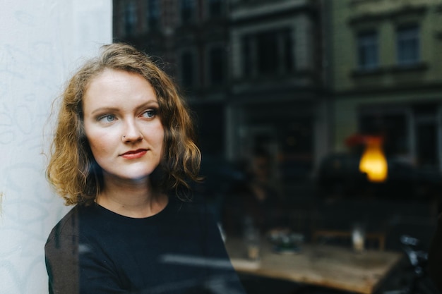 Thoughtful woman looking through window at cafe