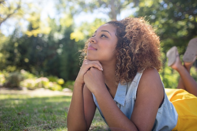 Thoughtful woman lying on a grass