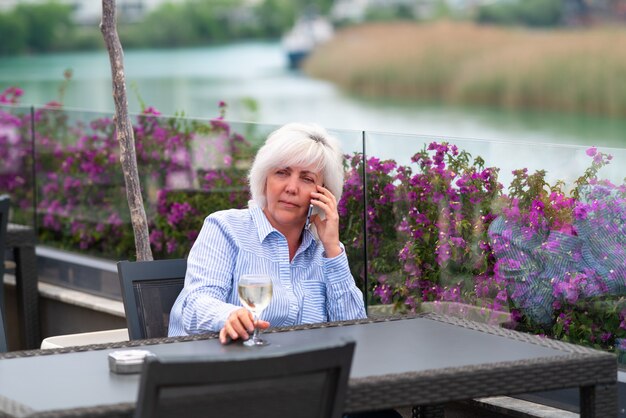 Thoughtful woman relaxing with a glass of wine and her mobile