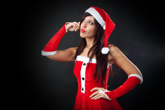 Foto donna riflessiva in costume di babbo natale in piedi su sfondo nero