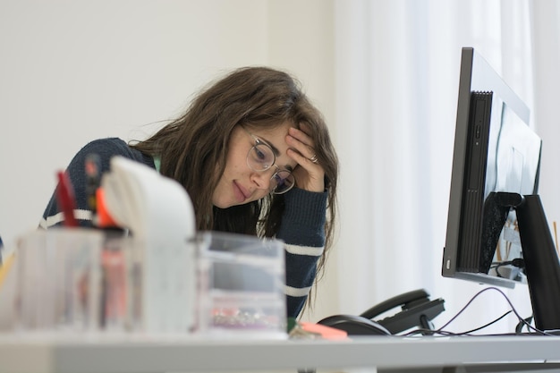 Photo thoughtful woman sitting by computer on table