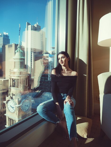 Photo thoughtful woman sitting on window sill