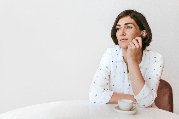 Thoughtful woman sitting with a cup of coffee