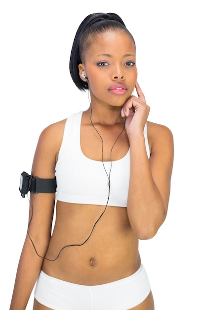 Thoughtful woman in sportswear listening to music