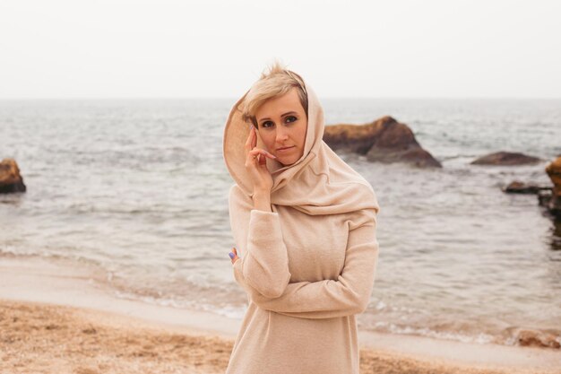 Thoughtful woman wearing dress near sea in autumn