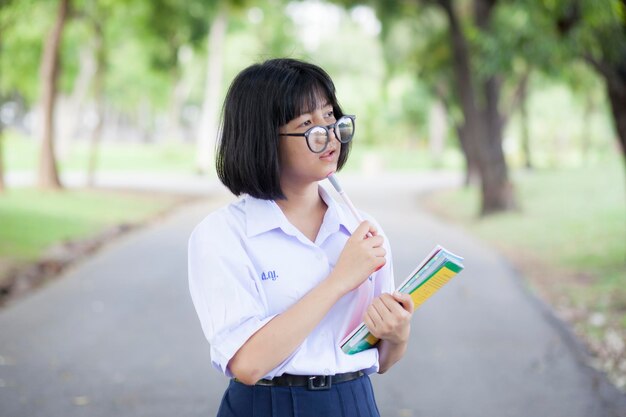 사진 도로 에 서 있는 책 과 펜 을 들고 있는 사려 깊은 여자