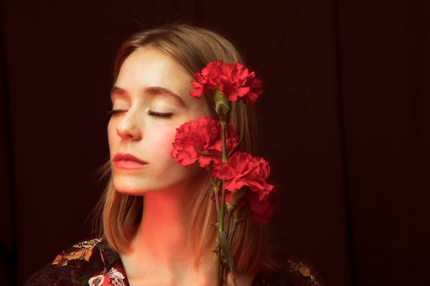 Photo thoughtful woman with red carnations