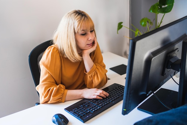 Foto donna premurosa che lavora su un computer desktop in ufficio