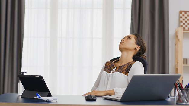 Thoughtful woman working from home looking at laptop.