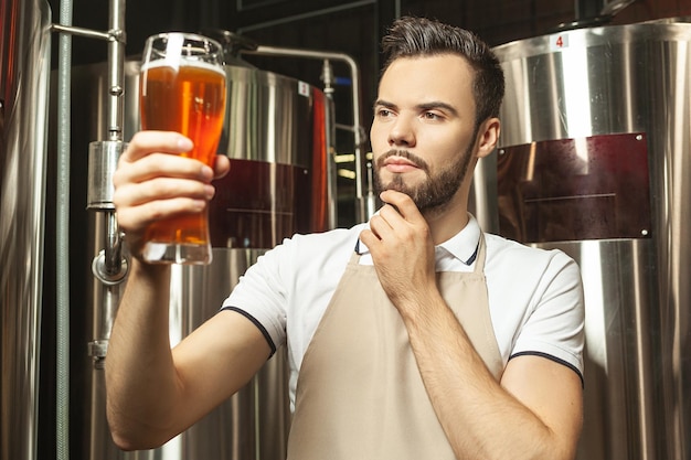 Thoughtful worker looking at the quality of at beer at brewery