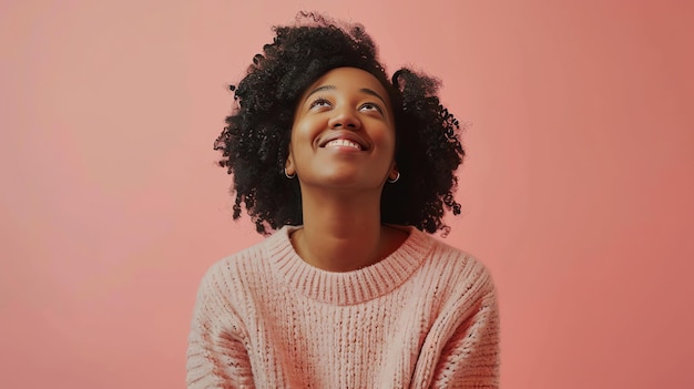 Thoughtful young AfricanAmerican woman looking up with a dreamy smile on her face against a pink background