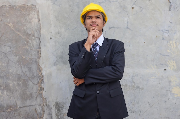 Photo thoughtful young asian project manager standing at construction site of building