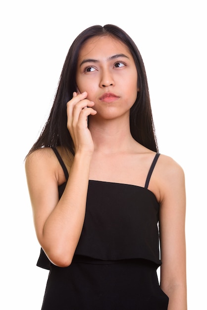 Thoughtful young Asian teenage girl talking on mobile phone