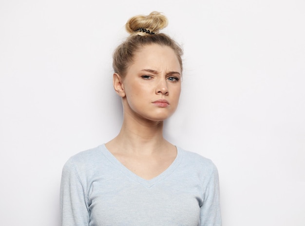 Thoughtful young blond woman against white background