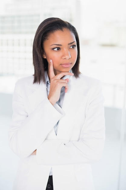 Thoughtful young dark haired businesswoman posing looking away