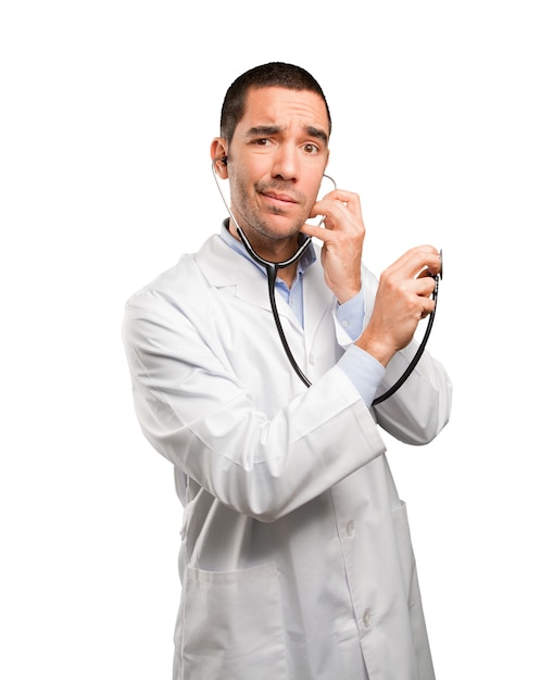 Thoughtful young doctor using a stethoscope