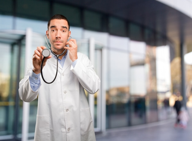 Thoughtful young doctor using a stethoscope