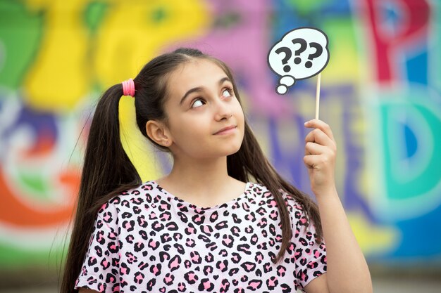 Thoughtful young girl holding up question marks