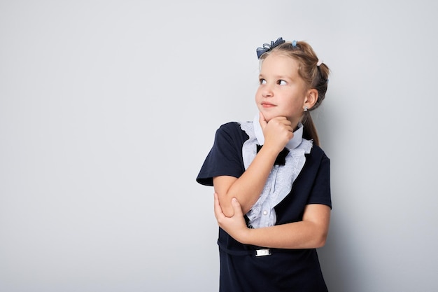 Thoughtful young girl looking away with hand on chin isolated on a light background