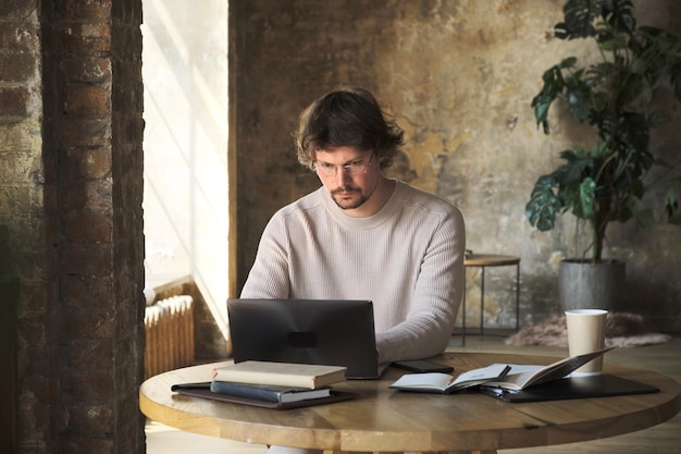 Thoughtful young man freelancer typing on laptop at home.