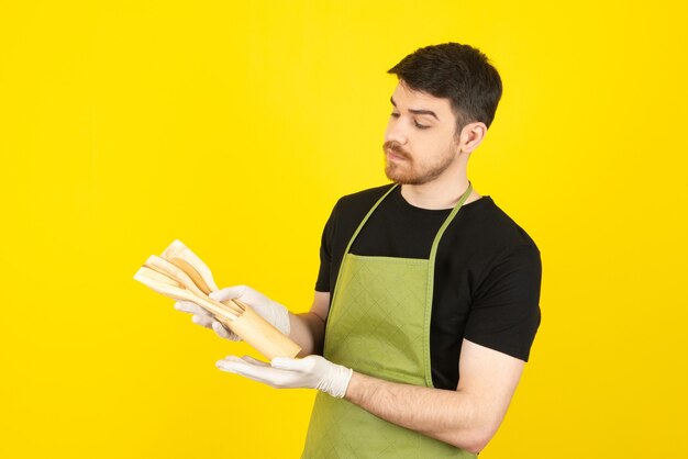 Giovane premuroso che esamina i cucchiai su un giallo.