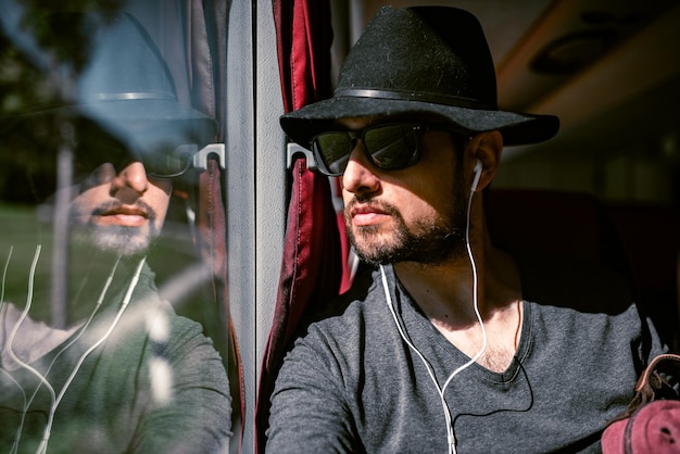 Thoughtful Young man riding on a train looking out the window thoughtfully