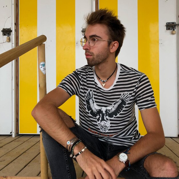 Thoughtful young man sitting by railing outdoors