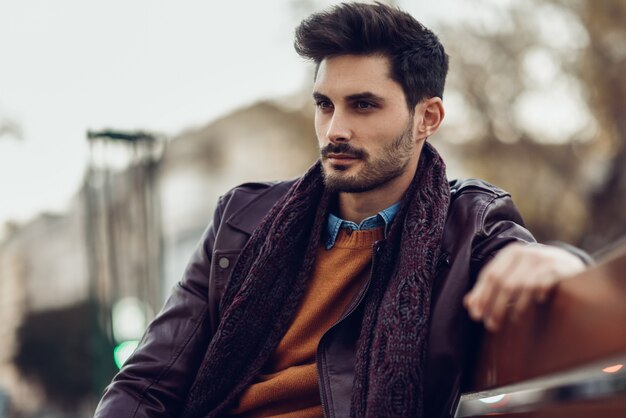 Thoughtful young man sitting on an urban bench. 