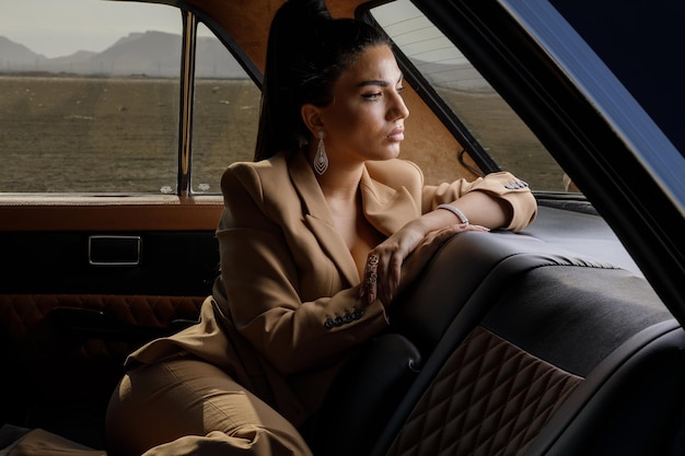 Thoughtful young model sittin in a car and looking away