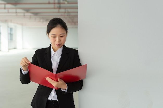 Thoughtful young pretty woman holding file and pencil business lady thinking touching face with pencil and looking away planning concept isolated front view on white background