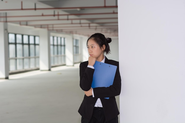 Thoughtful young pretty woman holding file and pencil business\
lady thinking touching face with pencil and looking away planning\
concept isolated front view on white background