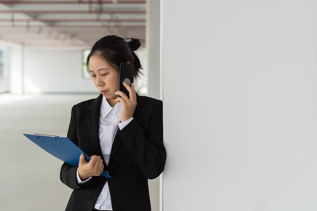 ファイルと鉛筆を保持している思慮深い若いきれいな女性ビジネス女性鉛筆で顔に触れるとよそ見を考える白い背景の上の計画概念分離フロント ビュー