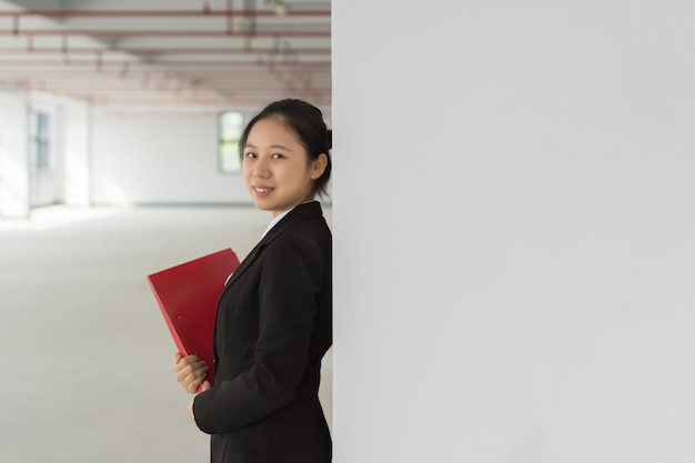 Thoughtful young pretty woman holding file and pencil business\
lady thinking touching face with pencil and looking away planning\
concept isolated front view on white background