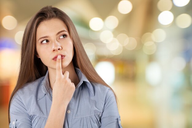 Thoughtful young woman holding finger on her lips