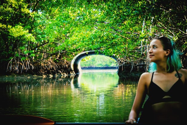 Photo thoughtful young woman kayaking in river at forest