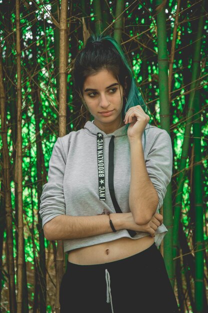 Photo thoughtful young woman looking away against trees in forest