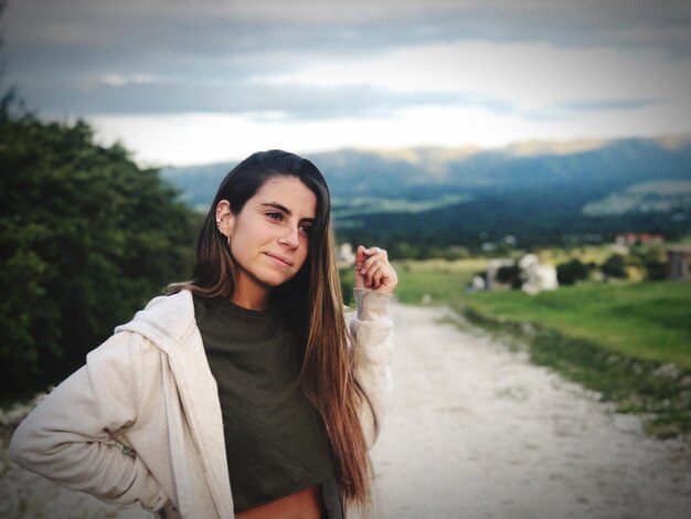 Foto giovane donna riflessiva che guarda da un'altra parte mentre si trova sulla strada sterrata