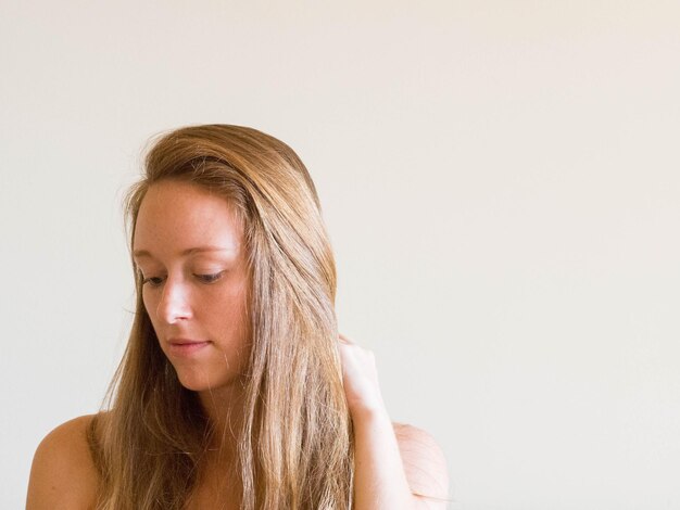 Photo thoughtful young woman looking down against white wall