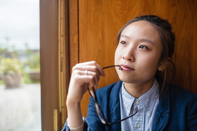 Thoughtful young woman looking through window