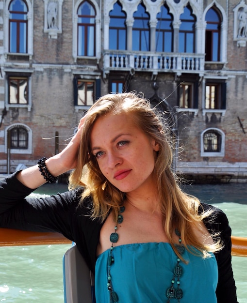 Photo thoughtful young woman sitting by grand canal against building