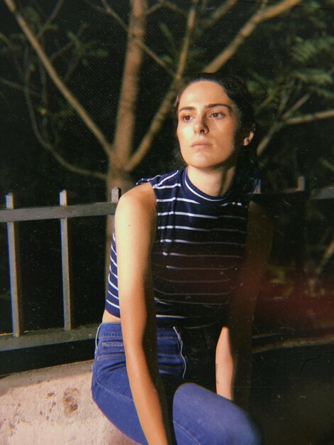 Photo thoughtful young woman sitting on railing at night