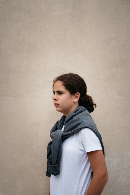 Photo thoughtful young woman standing against wall