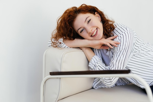 Photo thoughtful young woman staring intently ahead at the camera relaxes on a sofa at home