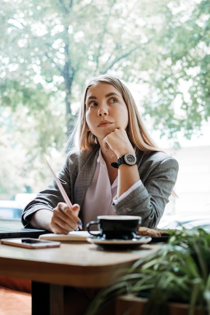 Thoughtful young woman student girl think at workplace at cafe professional content creator