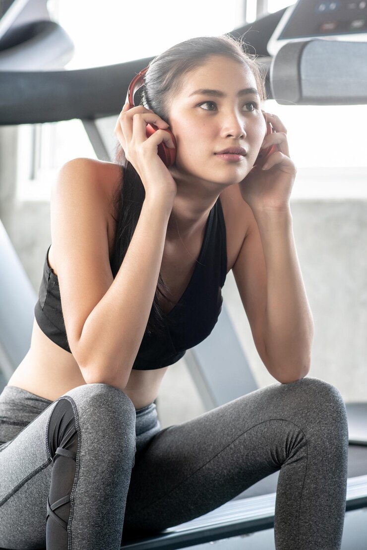 Photo 체육관 에서 트레드밀 에 앉아 있는 동안 헤드폰 을 착용 한 사려 깊은 젊은 여자