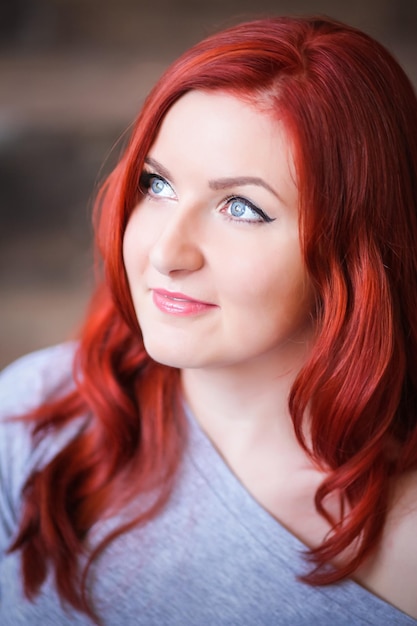 Вдумчивая молодая женщина с окрашенными рыжими волосами