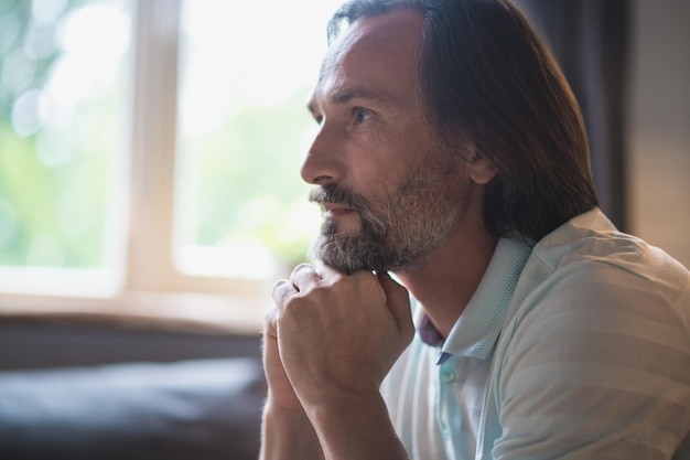 In thoughts. Mature bearded man sitting with a thoughtful look